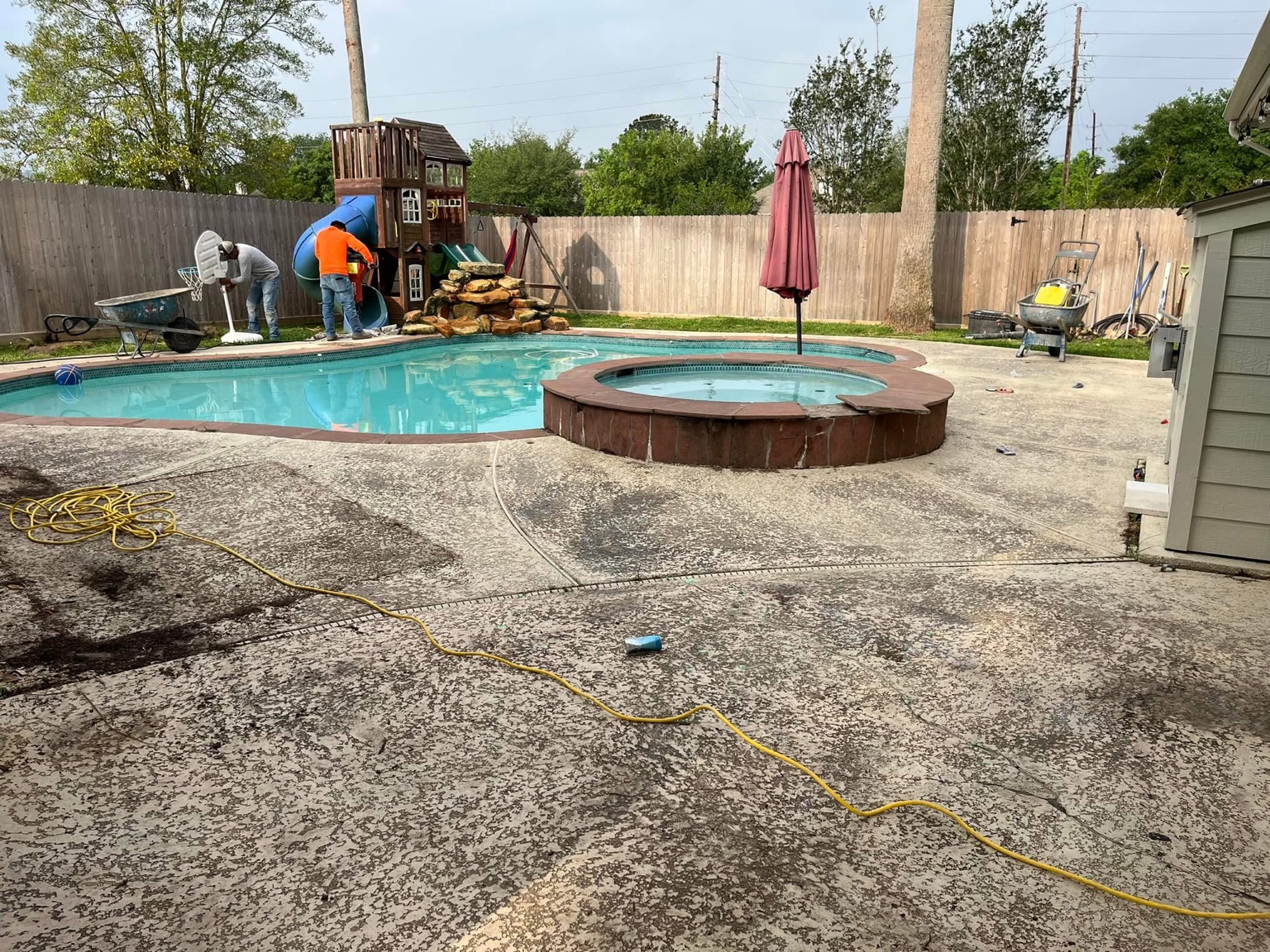 Before view of a worn concrete pool deck and raised spa in Katy, Texas